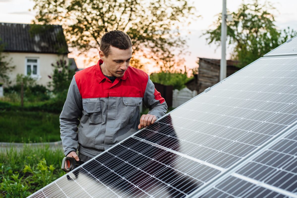 Man installing solar panels. An electrician or engineer works with solar panels. Image: Adobe Stock