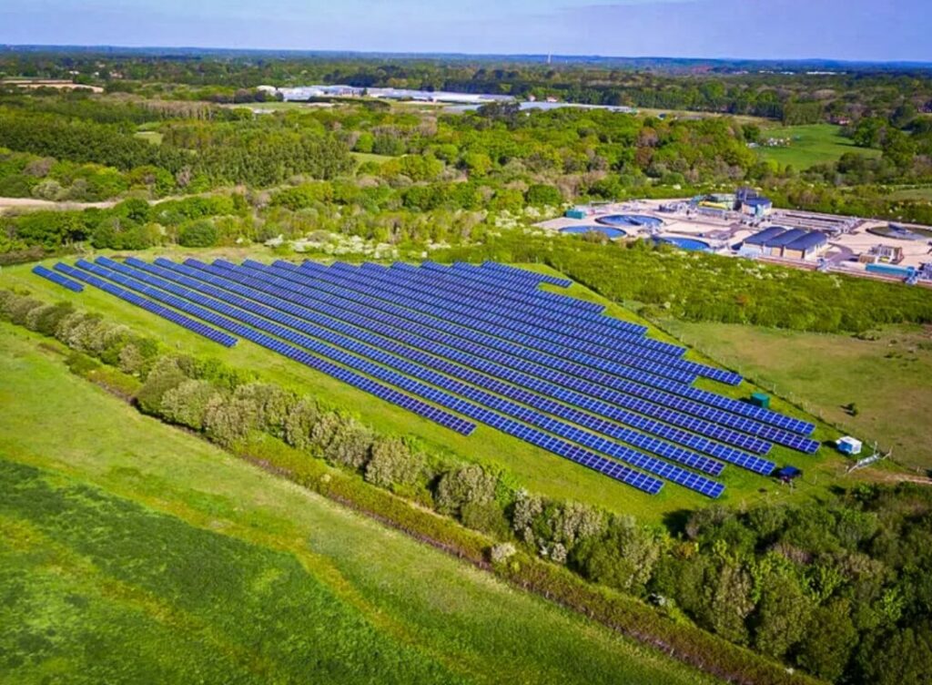 An aerial shot of a solar farm surrounded by green trees.