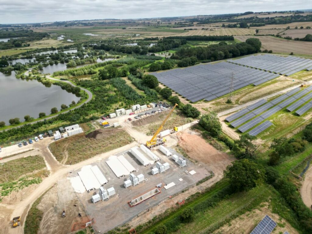 An aerial shot of a BESS and solar farm with trees surrounding it.