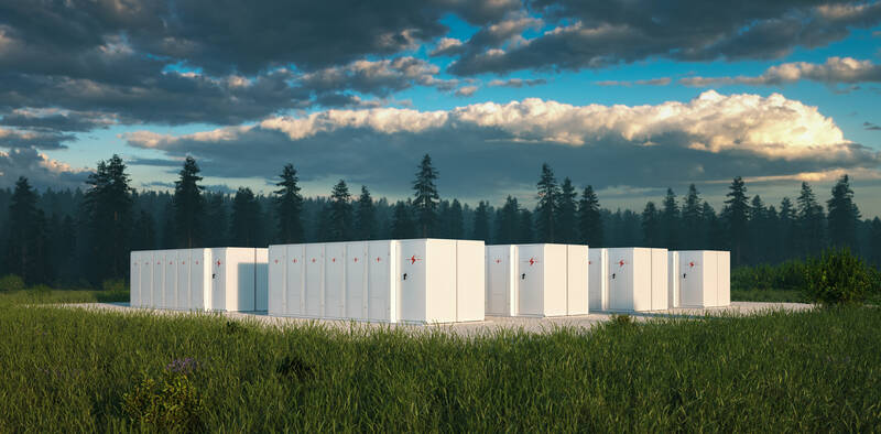 A battery energy storage system in front of trees underneath a blue sky with dark clouds