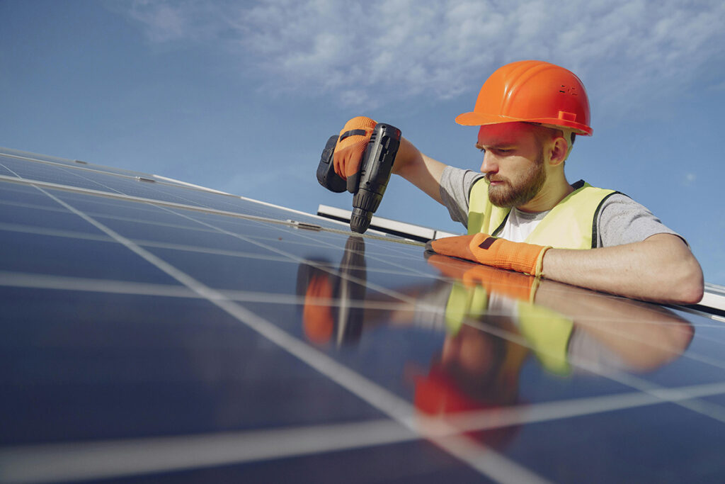 solar energy worker in hard hat and hi-vis installing solar PV modules