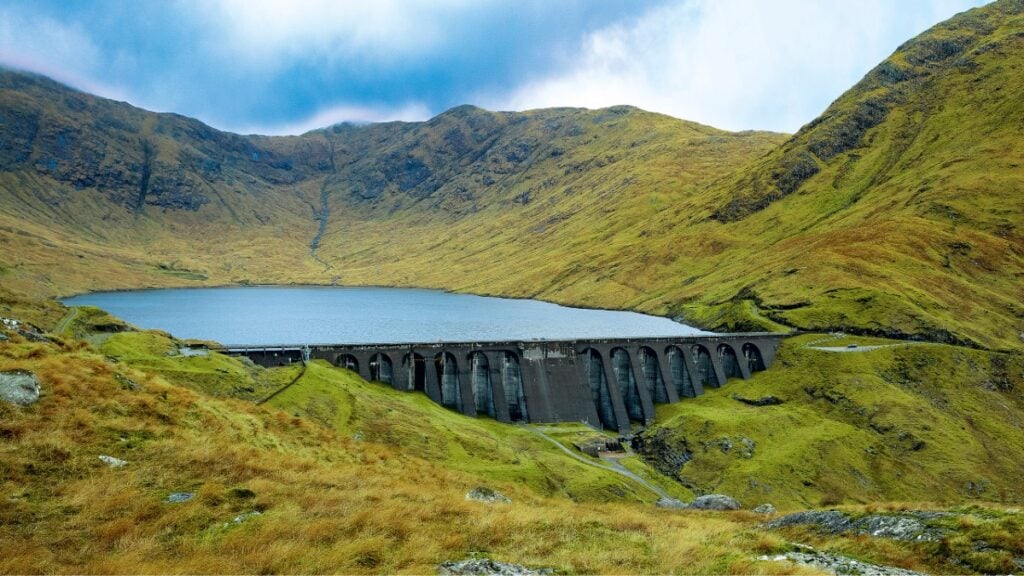 a large dam in rolling green hills