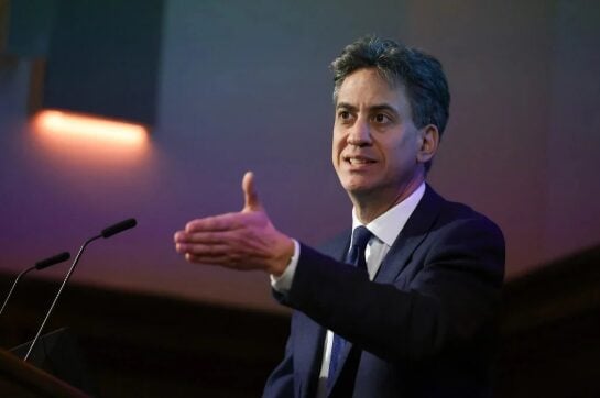 Energy secretary Ed Miliband speaks and gestures out a hand on stage