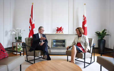 Prime Minister Kier Starmer and Welsh First Minister Eluned Morgan sit opposite each other in chairs in a white room in front of UK and Welsh flags