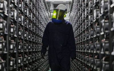 A man in a full face protective mask stands between battery storage systems