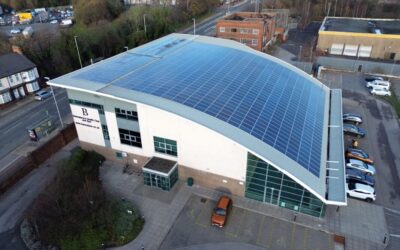 A building with a sloping, curved roof covered in solar panels