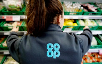 a person with long hair in a ponytail stands with their back to the camera wearing a co-op uniform