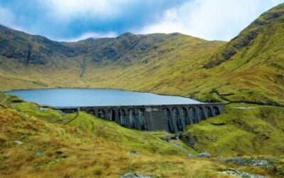 a large dam in rolling green hills