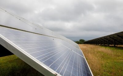 A solar panel in a field under a cloudy sky