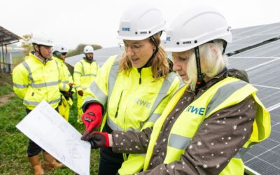 Two women look at a clipboard in front of solar panels