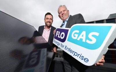 Two men hold the flogas logo next to a pv panel