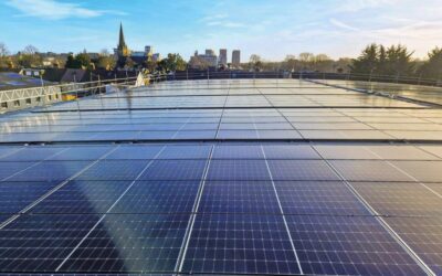 Solar panels on a flat rooftop with a city in the background
