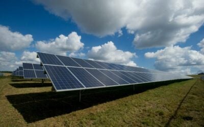 solar panels under a blue sky with large puffy clouds.