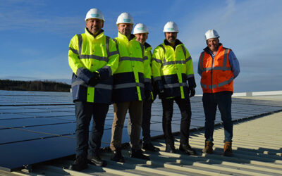 Men in hard hats stand near a rooftop solar panel