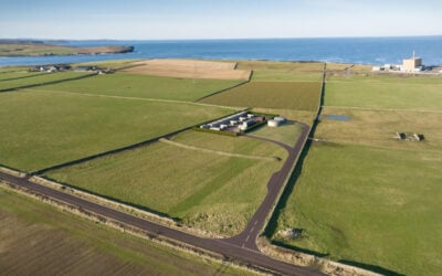 a 3d render of the Dounreay BESS project, surrounded by green fields and a view of the sea