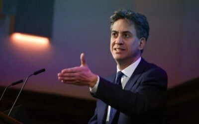Energy secretary Ed Miliband speaks and gestures out a hand on stage