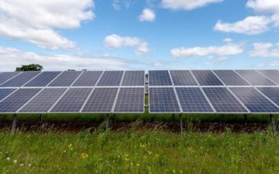 solar panels with blue sky and clouds above and green grass below