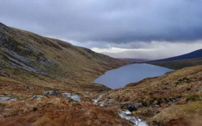 a scottish loch with rolling hills surrounding it