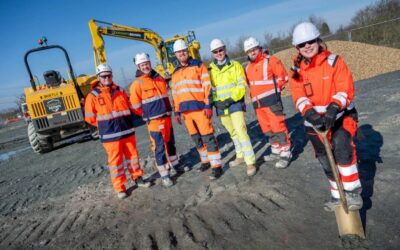 people in hi-vis vests hold a golden shovel and smile