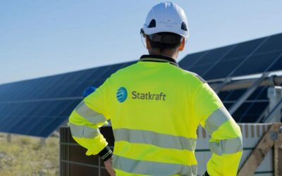 a man in a statkraft branded vest faces away from camera and towards a solar panel